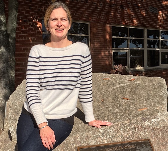 Irving Middle School Principal Cindy Conley is pictured on the rock in front of the school, a gift from previous students, staff, and principals in celebration of 50 years of education.
