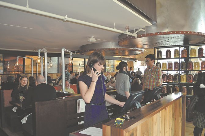 Hosts Melissa Walch and Christopher Tomoche with Hospitality Coordinator Cameron Jenson work the lunch hour rush at Founding Farmers restaurant in Potomac. The restaurant boasts a menu featuring local ingredients sourced from sustainable producers. 