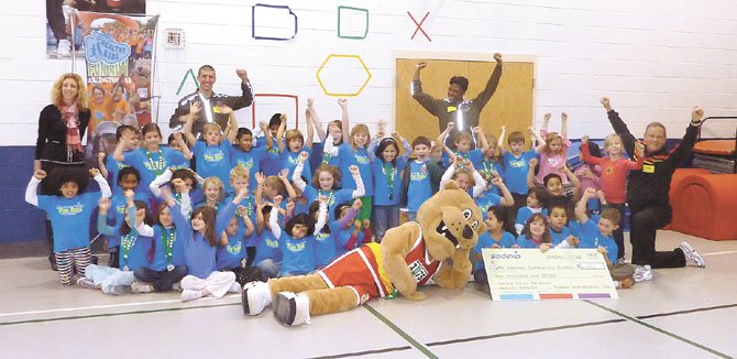 Mount Vernon Community School vice principal Elizabeth Namba, back left, and Marine Corps Marathon race director Rick Nealis, right, celebrate the Healthy Kids Award with students who participated in the Healthy Kids Fun Run last October. The school received a check for $1,000 for its top five placement with 115 registered runners.