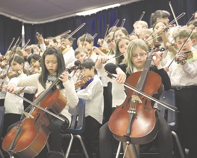 Adaline L. and Isobel Cobb, with 86 of their classmates, warm up on their cellos. The 88 beginners, in addition to their 54 colleagues in the Advanced Orchestra, delighted the audience of parents, family and staff with 10 tunes.