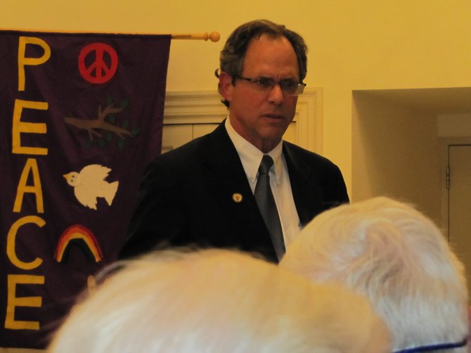 County Council President Roger Berliner faced an angry crowd in Potomac last week, in contrast to the banners behind him.
