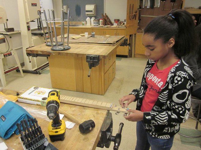 A Hammond Middle School student adjusts the tuning pegs on her cigar box guitar as part of the ASF building program.