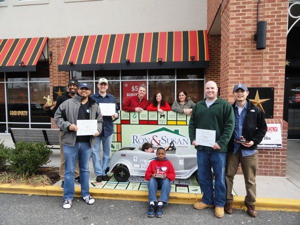 Ron Kowalski (back left) and Susan Borrelli (back right) stand with winners of last year’s annual Monopoly Tournament in front of Glory Days Grill in Lorton, which hosted the event to raise money for Habitat for Humanity of Northern Virginia. This year’s tournament will be held Saturday, Feb. 25 from 9 a.m. to 2 p.m. at the Workhouse Arts Center. 

