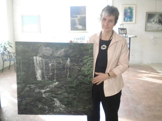 Artist Mary Hawkins with her painting of a waterfall that will be featured in this month's show, Visions of the Earth.