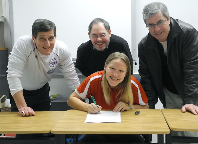 Masha Harmon, a senior at Yorktown High School, has signed a national letter of intent to play soccer at Davis & Elkins College in Elkins, W. Va. Three of her soccer coaches attended the signing ceremony. They are, flanking Masha, John McAuley, who coached Masha on the Arlington Fury, an Arlington Travel Soccer team on which she played from 2004 through 2009, and now coaches her on the Arlington Intensity Red; and Bob Weil, who coached her for three championship seasons in 2010 and 2011 on the FPYC (Fairfax Police Youth Club) Freedom. In the back row are Bruce Harmon, Masha’s father; Paul Carver, who coached her from kindergarten through seventh grade on the Arlington Aces, a house team on which she was the only girl; and Jean Christensen, Masha’s mother.
