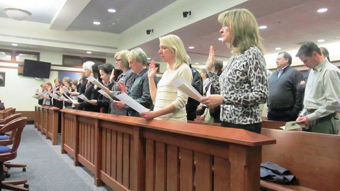 Fairfax County’s 16 newly-trained court-appointed special advocate (CASA) volunteers raise their hands to take the CASA oath during a swearing-in ceremony at the Jennings Judicial Center in Fairfax on Feb. 21. From left, Diane Brody, Rebecca Burke, Susan Chibnall, Susan Evans, Lynn Foster, Anne Havlovick, Lauren Janik, Sheila Kinderman, Patricia Larsen, Peggy McGannon, Denise Hall, Alicia Richie, Kitchy Sawets, Ann Sherwood, Joanne Shumpert and Nicki Watts.