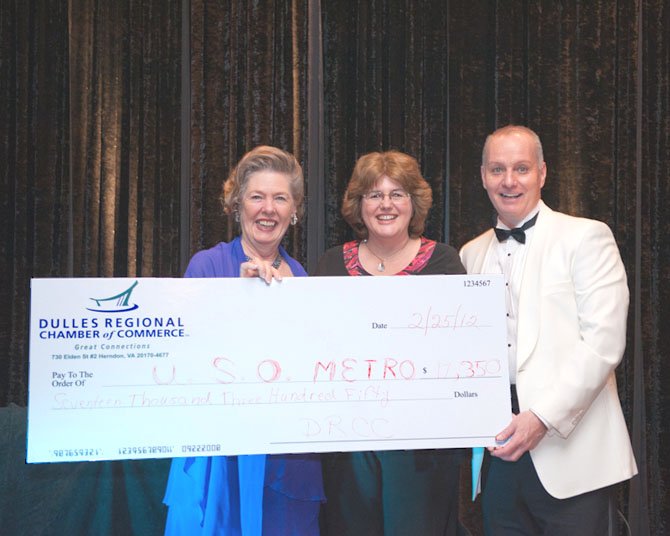 Dulles Regional Chamber President Eileen Curtis, left, and Chamber Board of Directors Chairman Kirk Forman, right, present the proceeds of the paddle auction to USO Metropolitan Washington representative Pam Horton, center.