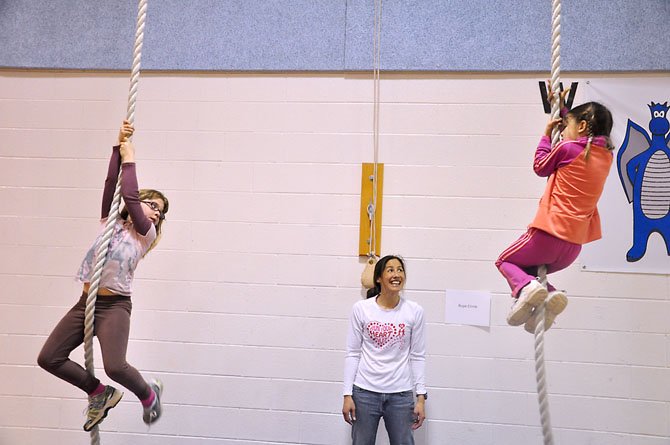 From left, Sarah McGrath and Sophia Ambrose, first graders at Colvin Rum Elementary, try to climb the gym rope while volunteer Sabrina Thomas cheers them on. 