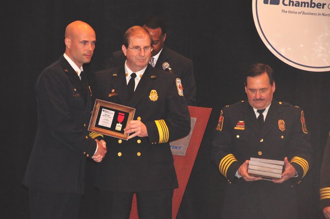 From right, Fairfax County Police Chief Col. David Rohrer and Fairfax County Fire Chief Ronald Mastin present Lt. Aron Corwin with a Bronze Medal of Valor for his efforts saving the life of five people during a swift water rescue in the Lorton area. 