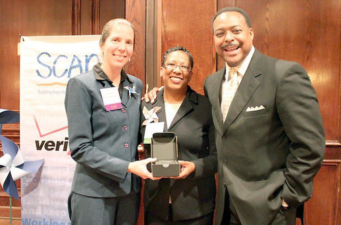 Sonia Quinonez, executive director of SCAN of Northern Virginia and event co-emcee ABC7's Leon Harris congratulate Valerie Cuffee.
