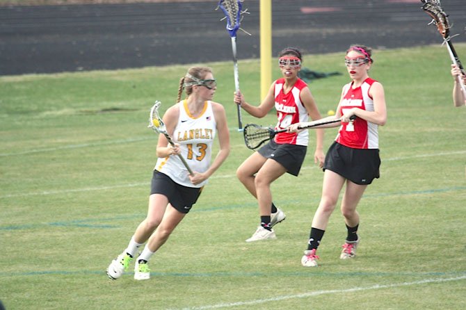 Langley High junior midfielder Hayley Soutter (13) goes to the goal during the Saxons' Liberty District home girls' lacrosse game versus McLean on March 28. Mackenzie May, a senior midfielder, is the Highlander on the right.