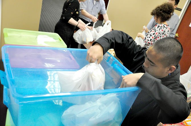 Patrick Francisco, a volunteer with Helping Hungry Kids, packs bagged meals for needy children into containers during the group’s weekly meal packing event Thursday, April 5. 