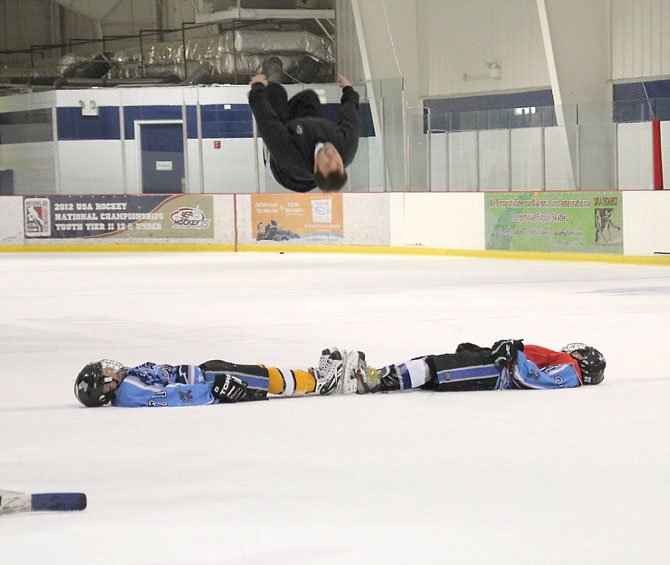 Nationally renowned figure skater Michael Weiss does a back flip over his son, Reston Raider player Chris Weiss, and teammate John Cardellicchio, as a reward for the local teams' having qualified for and being a part of the  12-under Tier II National Ice Hockey Championships. 