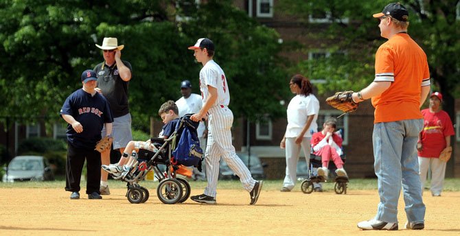 Nathaniel Ribyat with the T.C. Williams baseball team, pushes Tucker Riley around the bases as Owen Malone of the Alexandria Rugby Club looks on.
