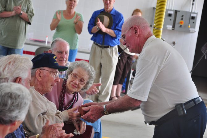 Past Great Falls Volunteer Fire Chief Homer Johns presents Milburn Sanders, who joined the department 70 years ago, with a brick from the original station Saturday, May 5. 