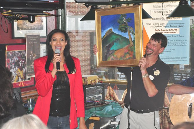 Christy Winters Scott, South Lakes women’s basketball coach and Washington Mystics commentator and Jimmy Cirrito, owner of Jimmy’s Old Town Tavern, auction off a painting to raise money for the legal fund to try and keep the Northern Virginia Training Center open. 