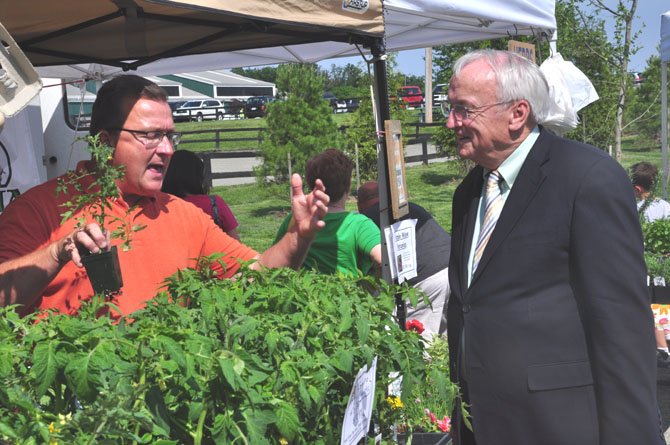 From left, Michael Anthony of Fossil Rock Farm speaks with USDA Under Secretary for Food, Nutrition and Consumer Services Kevin Concannon about the produce they offer at the Frying Pan Farm Park Farmer’s Market Thursday, May 17. 