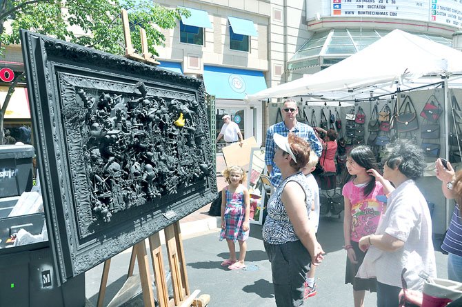 Guests at the Northern Virginia Fine Arts Festival examine a piece by mixed media 3D artist David Burton, made up of various action figures and toys. 