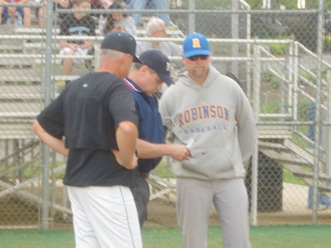 The team’s head coaches – Westfield’s Chuck Welch (left) and Robinson’s John James (right) – meet with the plate umpire prior to the start of the game. 