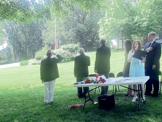 From left, Commander of VFW Post 5412, David Meyers, U.S. Rep. Gerry Connolly (D-11), State Sen. Dave Marsden (D-37), Del. Eileen Filler-Corn (D-41) and Supervisor John Cook (R-Braddock) salute the American flag as Rachel Goldman sings the National Anthem during the 7th annual Burke Memorial Day Ceremony on the grounds of the Burke Centre Conservancy on Monday, May 28.