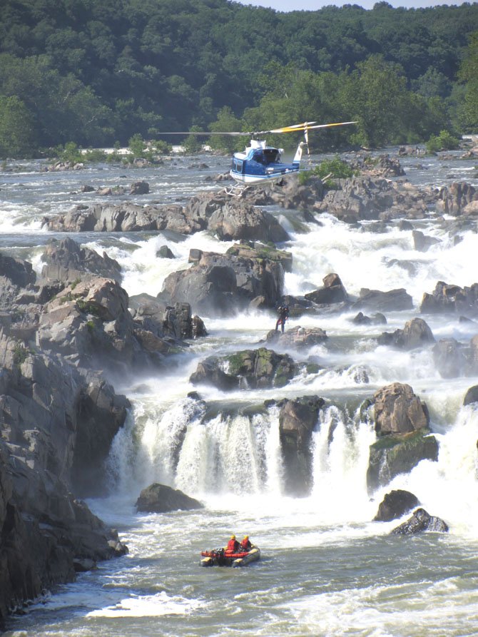 A rescue worker descends from a Park Police helicopter to the rock the kayaker was stranded on as boat units prepare nearby. Nikki Cheshire was awarded First Place in Breaking News Photo at the 2012 Virginia Press Association awards dinner on Saturday, April 20, 2013.