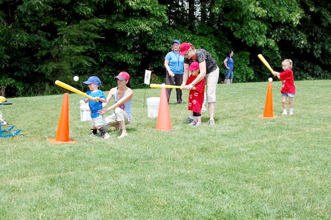 From left, preschoolers Joshua Tolboe, Hiba Hanabal, Kaylynn Hardman get help from their parents and teachers during batting practice at Cherry Run Elementary School’s Family Baseball Day on May 25.