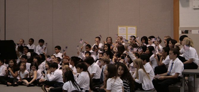 The Kings Glen fifth grade chorus waves American flags as the sixth grade All District Chorus sings a National Anthem medley.