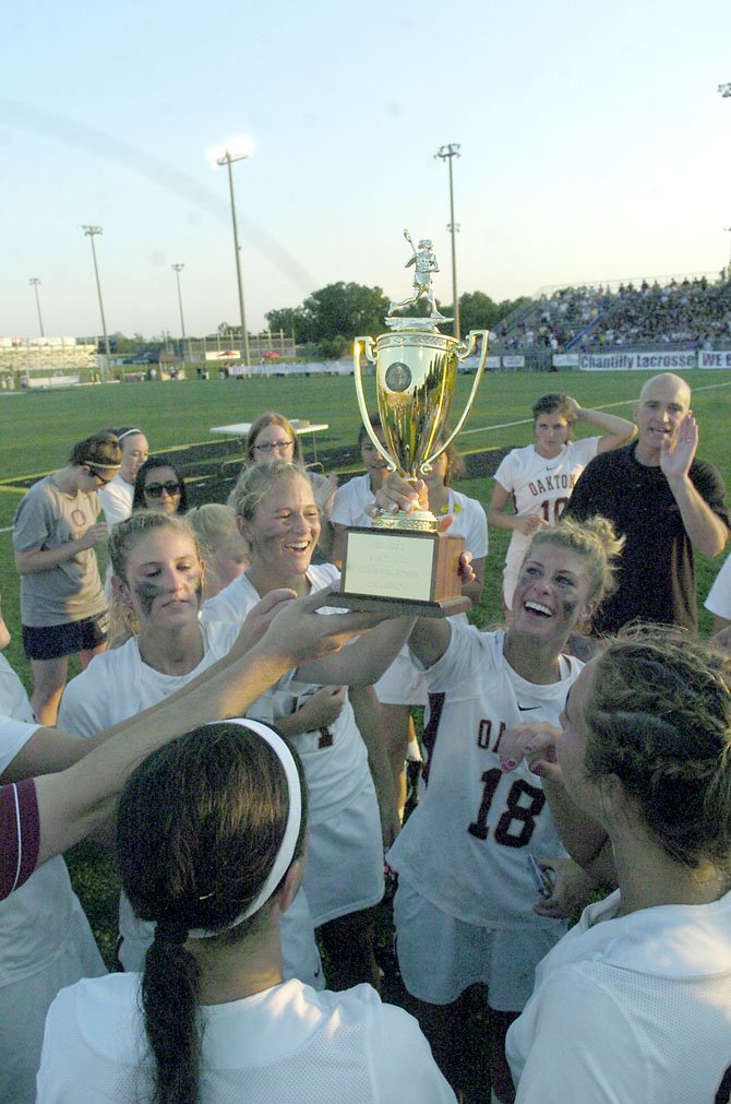 Oakton Cougars players, including senior attack Carly Palmucci (18), hold up the state championship trophy during postgame festivities. Palmucci had two goals and two assists in the victory.