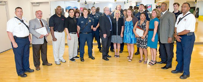 At a ceremony on June 18, Gary Oswald (center), wife Rosemary (to his left) and daughter Amber are surrounded by six of the seven civilians and some of the Fairfax County Fire and Rescue Department firefighters that worked together to save his life on Feb. 24. The Fairfax County Fire and Rescue Department presented Life Saving certificates to Mary Butler, Damian Hawkins, Min Huynh, Lori Jones, Nick Taktak, Sandy Weaver and Chuck Wright for their work as a "well-rehearsed team" to perform multiple and continuing lifesaving actions on Oswald.
