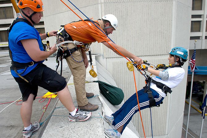 Special Olympics Virginia Athlete Rose Pleskow of Reston gets a helping hand from her ropes master Chris as she starts her 20 foot practice rappel above the entrance to the Crystal City Hilton in Arlington on June 22. After completing the 20 foot rappel, she’ll go to the 12th floor, climb up a flight of stairs to the roof, and rappel 100 feet down the outside of the building. 