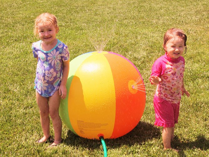 Cassie Geer, 3-1/2, and 2-1/2-year-old Anna Schustereder face off with a water-sprinkling ball.