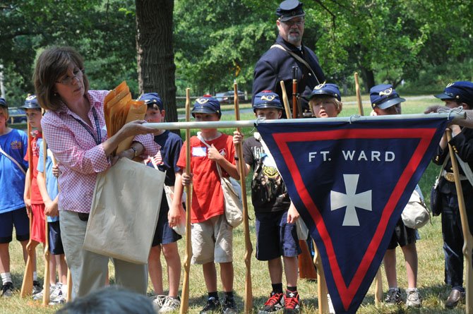 Susan Cumby displays headquarters flag that that was designed and made by camper Brendan Pagona after a lesson in Civil War flags and symbols. Brendan used the 5th Army Corp emblem, the Maltese Cross.
