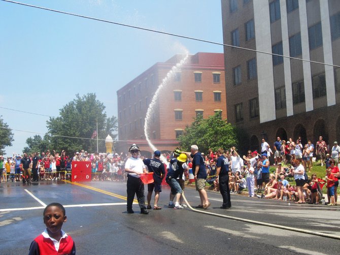 Firefighters from the City of Fairfax’s Volunteer Fire Department battle it out with other neighboring departments during the "Lay-a-Line" competition in which they shoot their fire hoses through a target – and spray the crowd - during the City of Fairfax’s annual Old-Fashioned Fireman’s Day event on July 4. 
