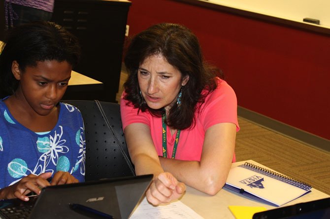 Ann Heidig of Taylor Elementary School in Arlington (right) helps Aliyah Ewell, a rising 6th grader at Mayfield Intermediate School in Manassas City Park, research the composition of space junk. 