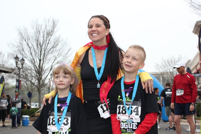 BethAnn Telford of Fair Lakes with her friend Julie’s children, Karissa and Landen Stitzel, at the Rev3 Run Rogue 5K in March at Fairfax Corner. Telford will compete in Ironman World Championship in Kona, Hawaii.