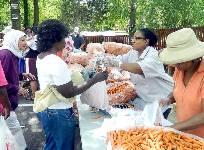 Venisa McCormick serves up the carrots, which arrived at Rising Hope in 50-pound sacks.
