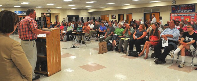 Approximately 150 Mount Vernon residents filled the cafeteria at Belle View Elementary School on Monday evening, July 30, for the Westgrove Park Master Plan public information meeting. Linwood Gorham, Mount Vernon representative on the Fairfax County Park Authority addresses the gathering. Standing to the right of Gorham is Sandy Stallman, Fairfax County park planning manager.
