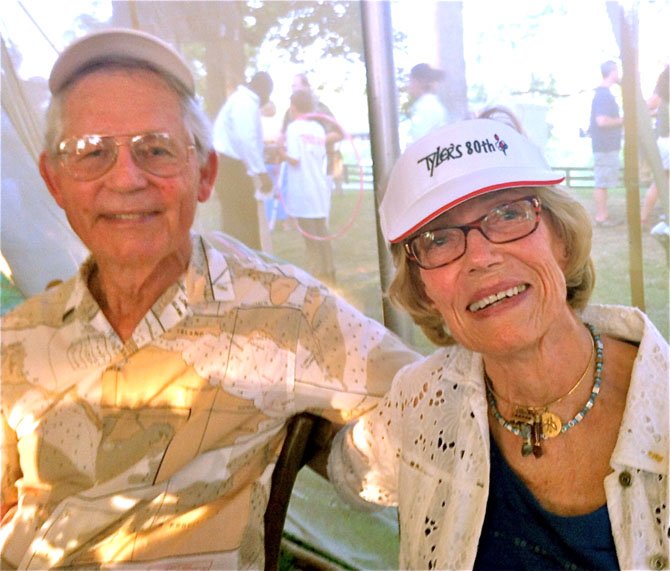 Tyler and Bess Abell share lunch with friends at his birthday celebration, while behind them, friends chat and watch the children try their skills at the hula-hoop.
