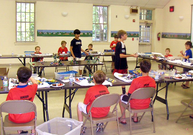 Standing, from left, Evan Cater and Cam Meyer explain LEGO building techniques to the young campers.
