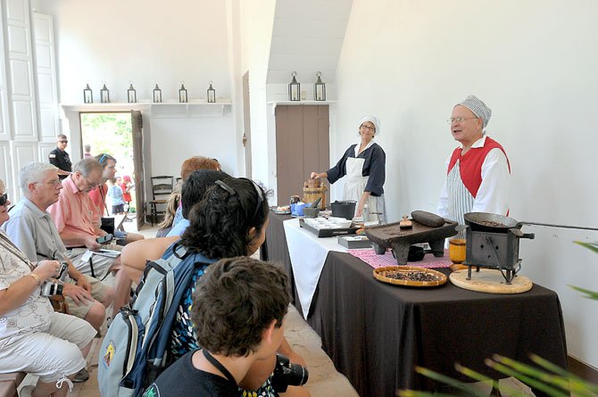 Karen Menatti and Ron Field, historic interpreters at the Mount Vernon Estate, entertain visitors with demonstrations on the making of colonial chocolate and ice cream.