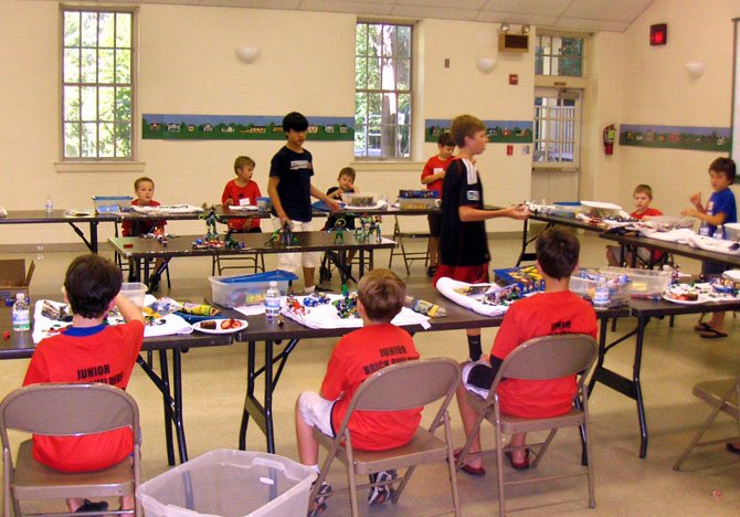Standing, from left, Evan Cater and Cam Meyer explain LEGO building techniques to the young campers.