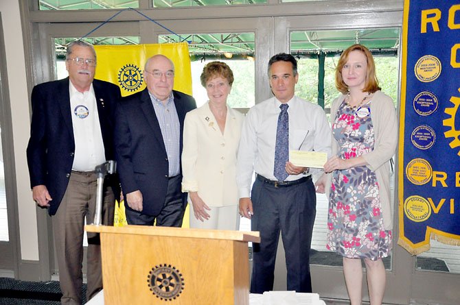 Members of the Reston Rotary Club hand Denise Kellogg (right), of the Colonial Williamsburg Foundation, funding for electronic field trips for six area elementary schools. 