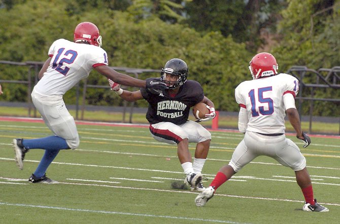 Senior running back Denzel Weaver looks to elude a pair of T.C. Williams defenders during a scrimmage on Aug. 23 at Herndon High School.