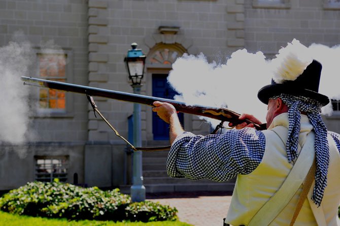 Virginia Infantry soldier Todd Brighton shoots off a volley of fire on the front green of the Carlyle House at the siege of the War of 1812 exhibit on Saturday, Aug. 18.