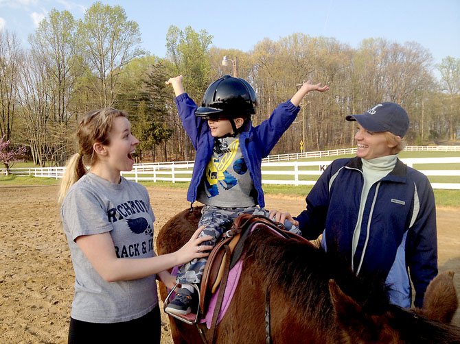 A young rider celebrates a new skill with trainers at the Northern Virginia Therapeutic Riding Program in Clifton.