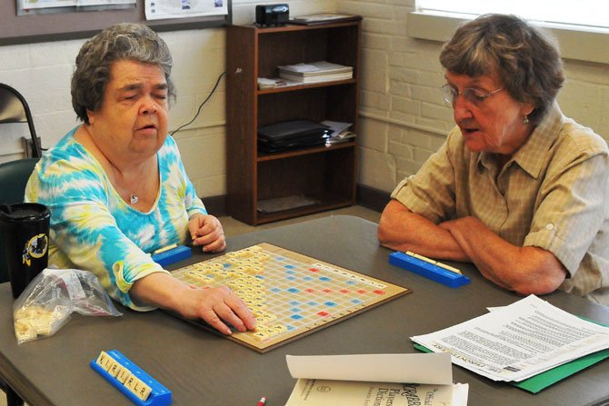 Judy Duncan takes her turn looking for a place to add a new word. Duncan is blind and brings in a Braille Scrabble set. Playing with Duncan are Josie Macdonald and Jean Hayden.
