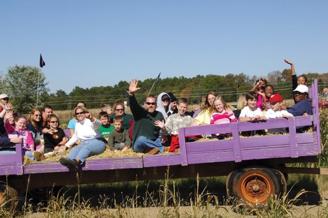 Visitors to Cox Farms enjoy a hayride. In the background are some of the giant slides.

