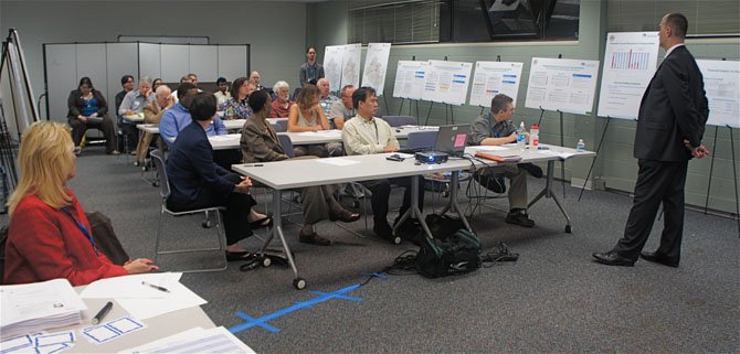 Director Tom Biesiadny addresses the attendees, surrounded by boards depicting the Fairfax County Dept. of Transportation's report on the state of transportation in the County and possible revenue options to meet transportation needs.