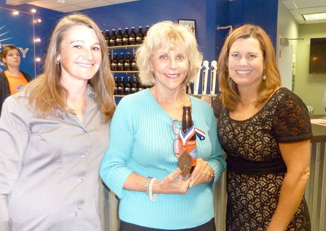 Port City Brewery's Jen Chace, Janet Barnett and Cathy Puskar at the Senior Services of Alexandria's Oct. 16 Oktoberfest to support Meals On Wheels. Barnett is holding Port City's bronze medal-winning Monumental IPA craft beer.
