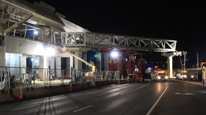 The first section of the pedestrian bridge across Route 123 into the McLean Station, aka Tysons East Metrorail Station, is put into place. At left, workers inside the station itself watch as crews connect the bridge section to the station.